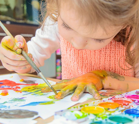 A little girl is painting with her hands.